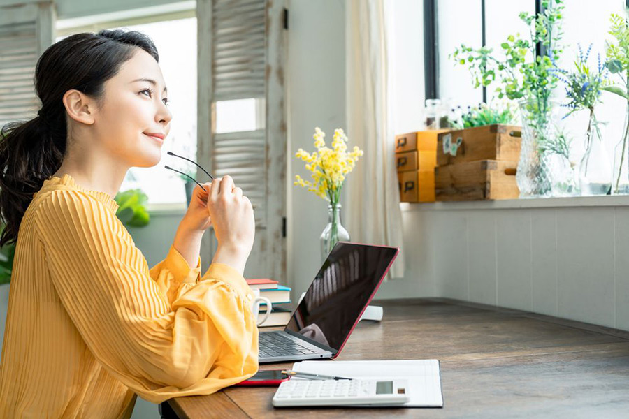 パソコン操作の息抜きに窓を眺める女性